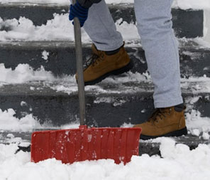 Close up of man shoveling snow off of stairs with red shovel