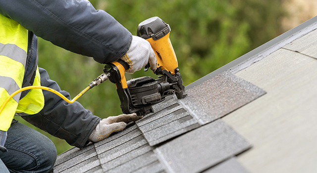 A contractor installing roof shingles