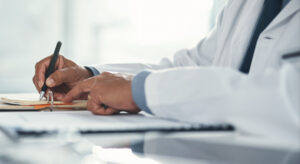 Close up of male doctor signing paperwork